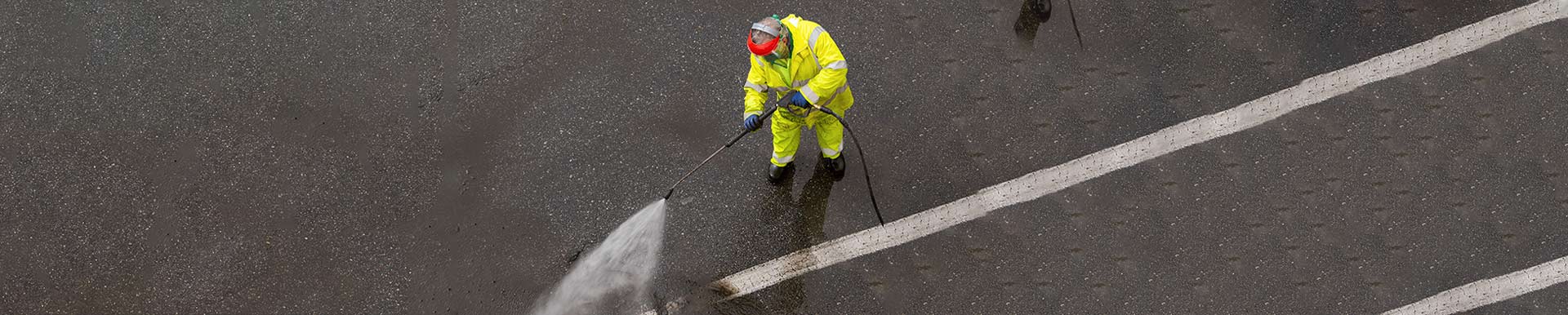 Worker cleaning a city road with high pressure water jet machine